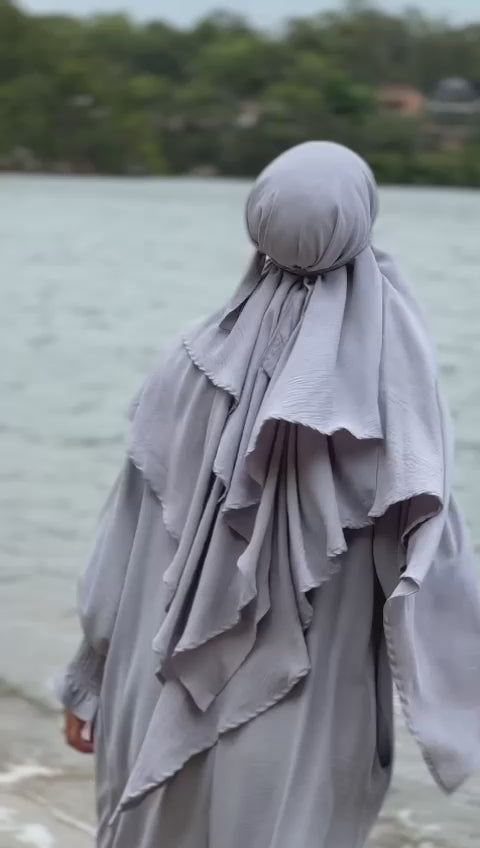 Indulge is an understated elegance of our Silver Grey Crepe Crinkle Abaya with Double Layer Khimar Set, a symbol of modesty and sophistication exclusively available at Hikmah Boutique. The modest design of silver grey offers an ensemble that seamlessly blends tradition and contemporary style with refined grace.