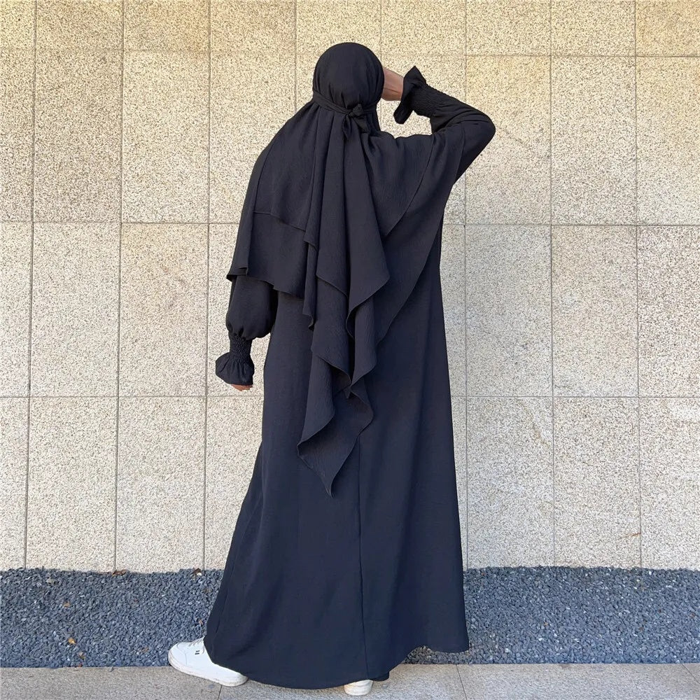 Immerse yourself in the allure of our Black Crepe Crinkle Abaya with Double Layer Khimar Set, an epitome of grace and sophistication exclusively available at Hikmah Boutique. The classic black hue transcends trends, delivering an ensemble that seamlessly merges tradition and contemporary style with understated elegance.