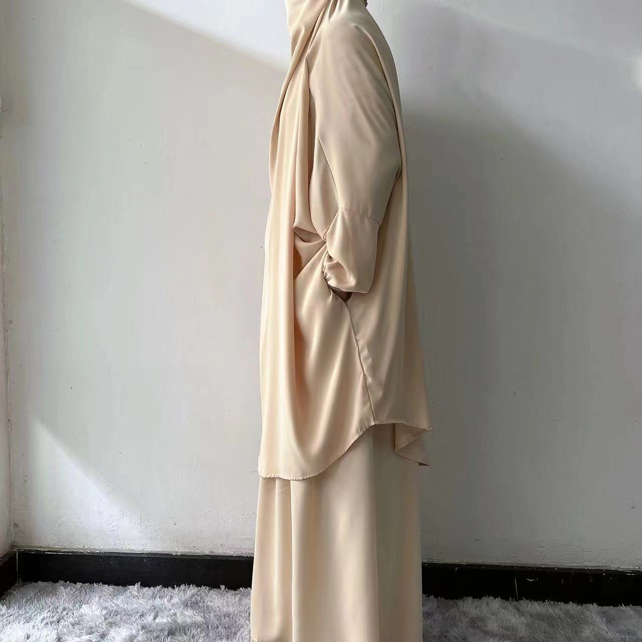 Step into serene elegance with our Cream Beige French Jilbab Prayer Set, exclusively at Hikmah Boutique. This one-size jilbab and skirt set with cuff sleeves is crafted from soft, breathable Nida fabric, providing ultimate comfort.