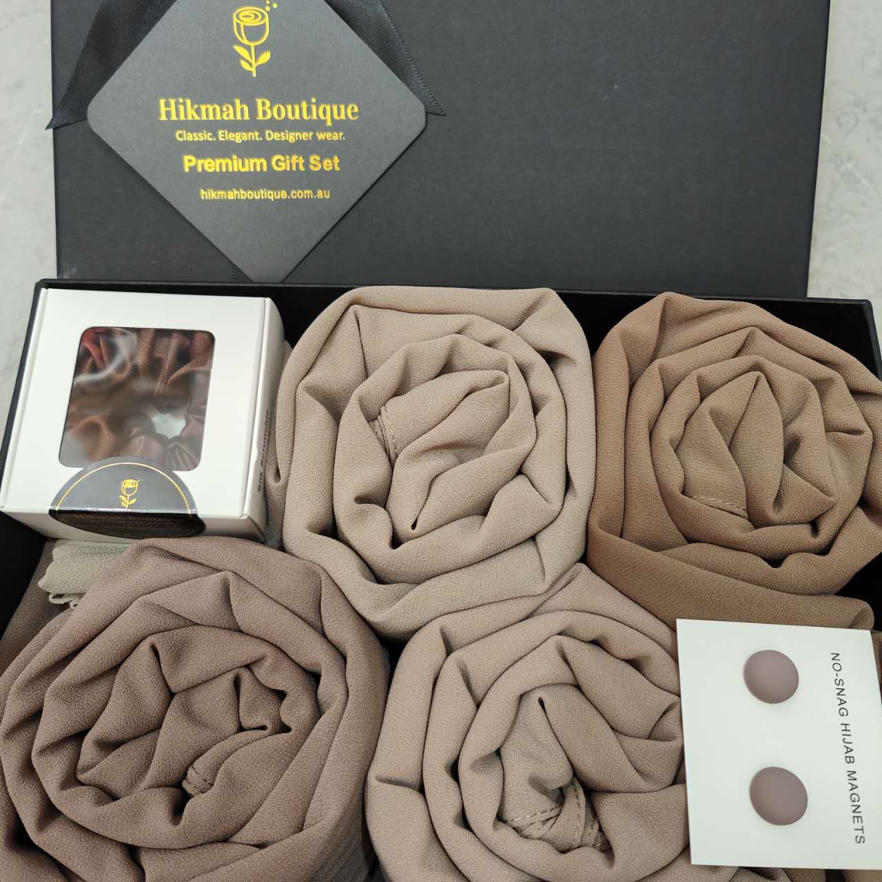 Indulge in the luxury of Hikmah Boutique's Chiffon Hijab Gift Box - The Tan Set. This gift box is the perfect style of sophistication, style and elegance. This set includes 4 premium quality chiffon hijabs in the most versatile colors of light taupe, chocolate, Desert Palm and Almandine, to suit every mood. Perfect Gift!