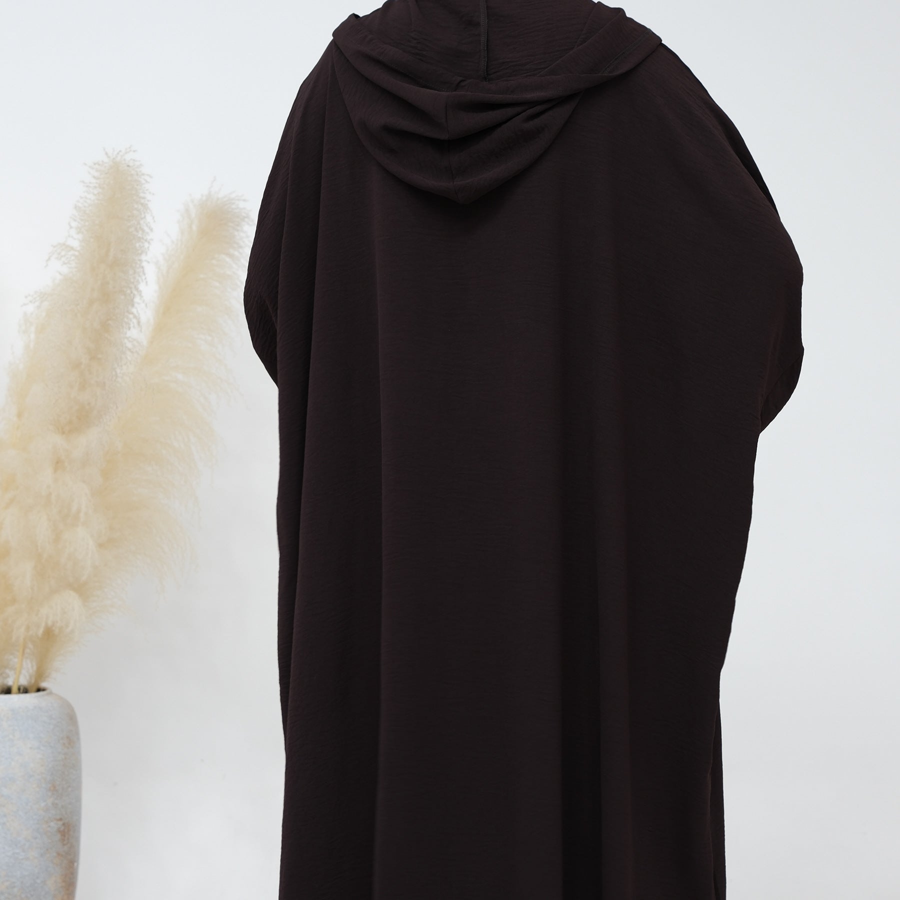 Indulge in the rich elegance of our Dark Coffee Hooded Jilbab Abaya, an embodiment of refined modesty exclusively available at Hikmah Boutique. Meticulously crafted with attention to detail, this exquisite garment is poised to elevate your modest wardrobe with sophistication and grace.