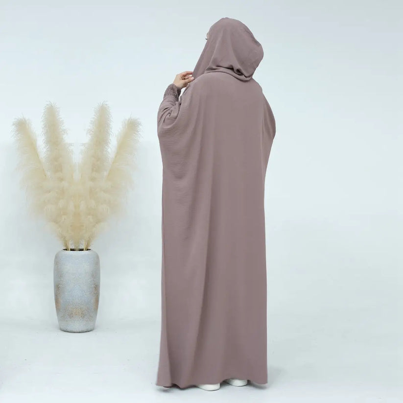 Experience the understated charm of our Dusty Mocha Hooded Jilbab Abaya, a symbol of subtle modesty exclusively offered at Hikmah Boutique. Meticulously crafted with attention to detail, this refined garment is designed to elevate your modest wardrobe with grace and sophistication.